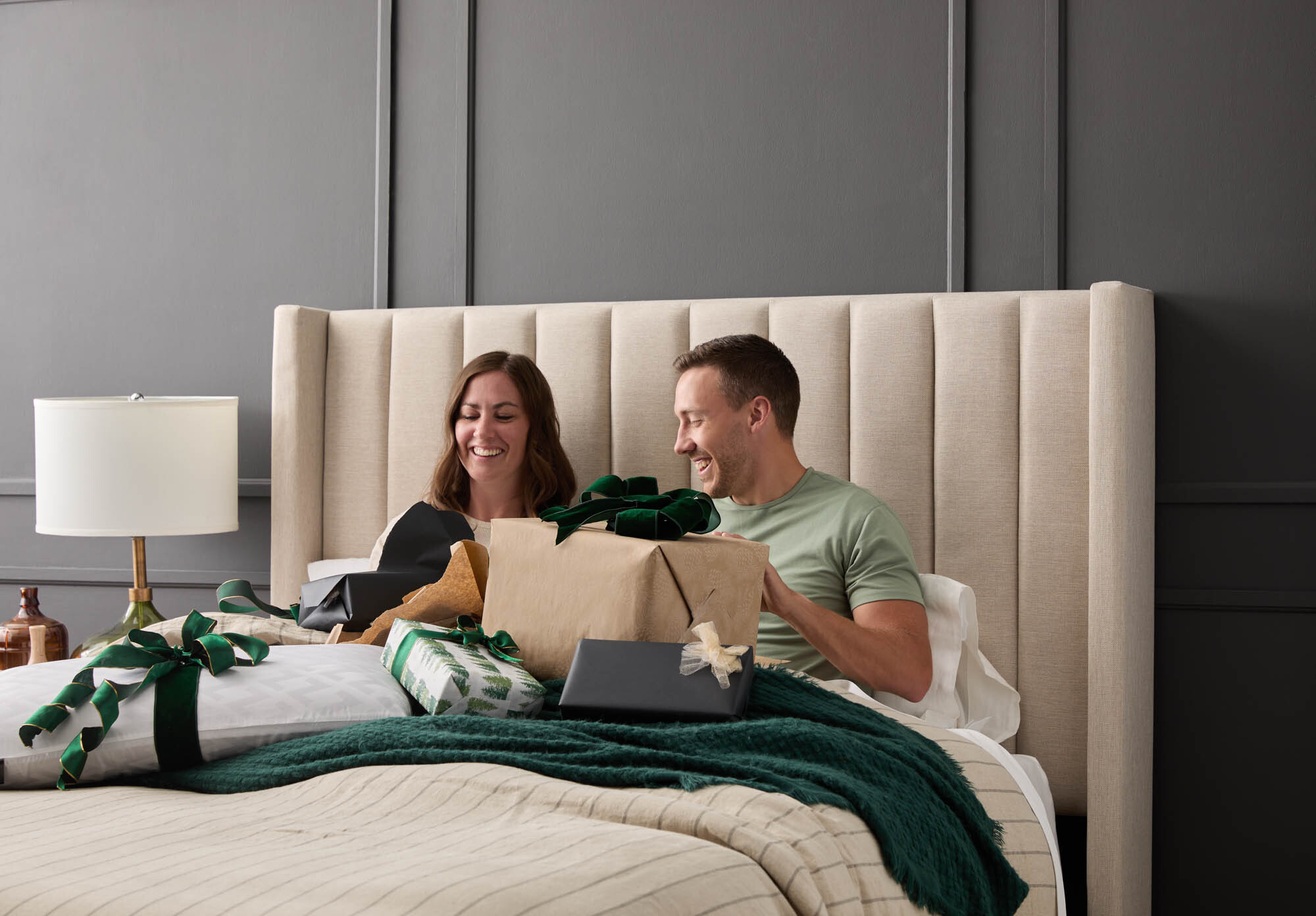 Couple laying in bed together opening presents